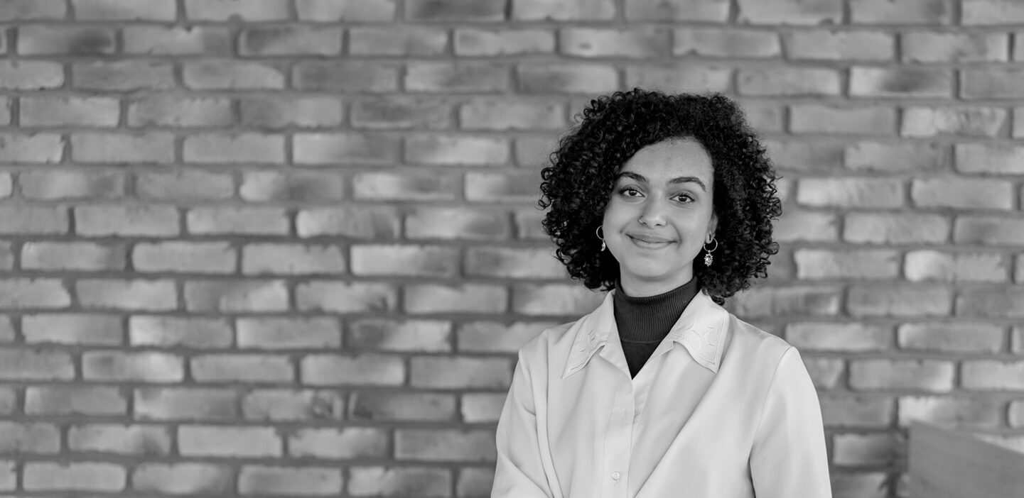 Smiling woman standing in front of a brick wall